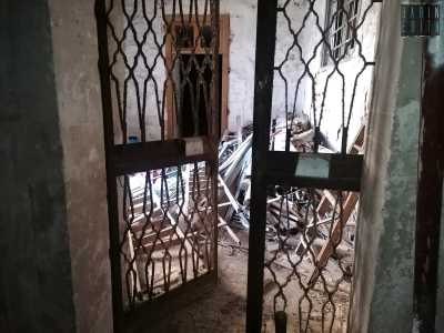 Saliamo la prima rampa e, attraverso una porta in ferro giungiamo in un vano voltato, pieno di materiale edilizio...